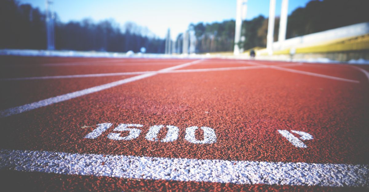 Empty running track lane with 1500 meter marking, sunny day outdoors.